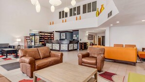 A spacious lobby with leather sofas, a reception desk, and a vending machine.