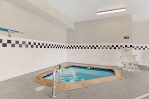 A small indoor pool with a checkered tile border, a spa timer sign, and a white lounge chair. - Quality Inn & Suites Denver International Airport (Aurora)