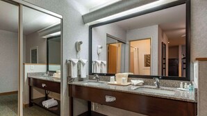 Un baño de hotel con lavamanos doble, un espejo grande y un secador de pelo.