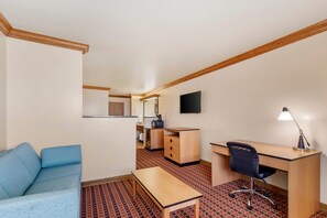 A compact room with a sofa, a desk, a chair, a television, and a small kitchenette. - Quality Inn & Suites Denver Airport - Gateway Park (Aurora)