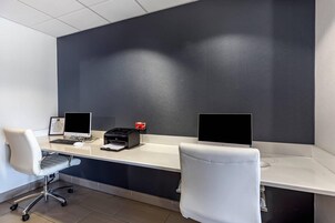 A modern office desk with two monitors, a printer, and a chair.