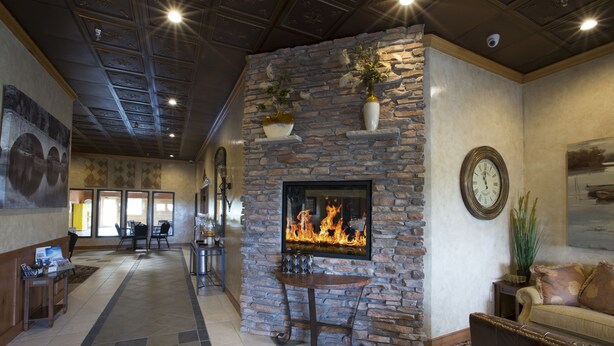 Un hall con chimenea de piedra, un reloj y una zona de estar con sofá y sillones.