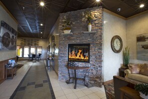 A lobby with a stone fireplace, a clock, and a seating area with a couch and chairs. - Miles City Hotel & Suites (Miles City)
