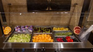 Un bufé con diversas frutas y vasos de yogur.