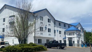 A multi-story hotel with a white exterior and blue roof. There is a parking lot with a black pickup truck parked in front. - Baymont by Wyndham Loveland/Fort Collins Area (Loveland)
