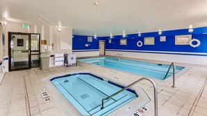 A swimming pool with a blue and white tiled floor, a glass door entrance, and a sign indicating the pool's depth. - Baymont by Wyndham Loveland/Fort Collins Area (Loveland)