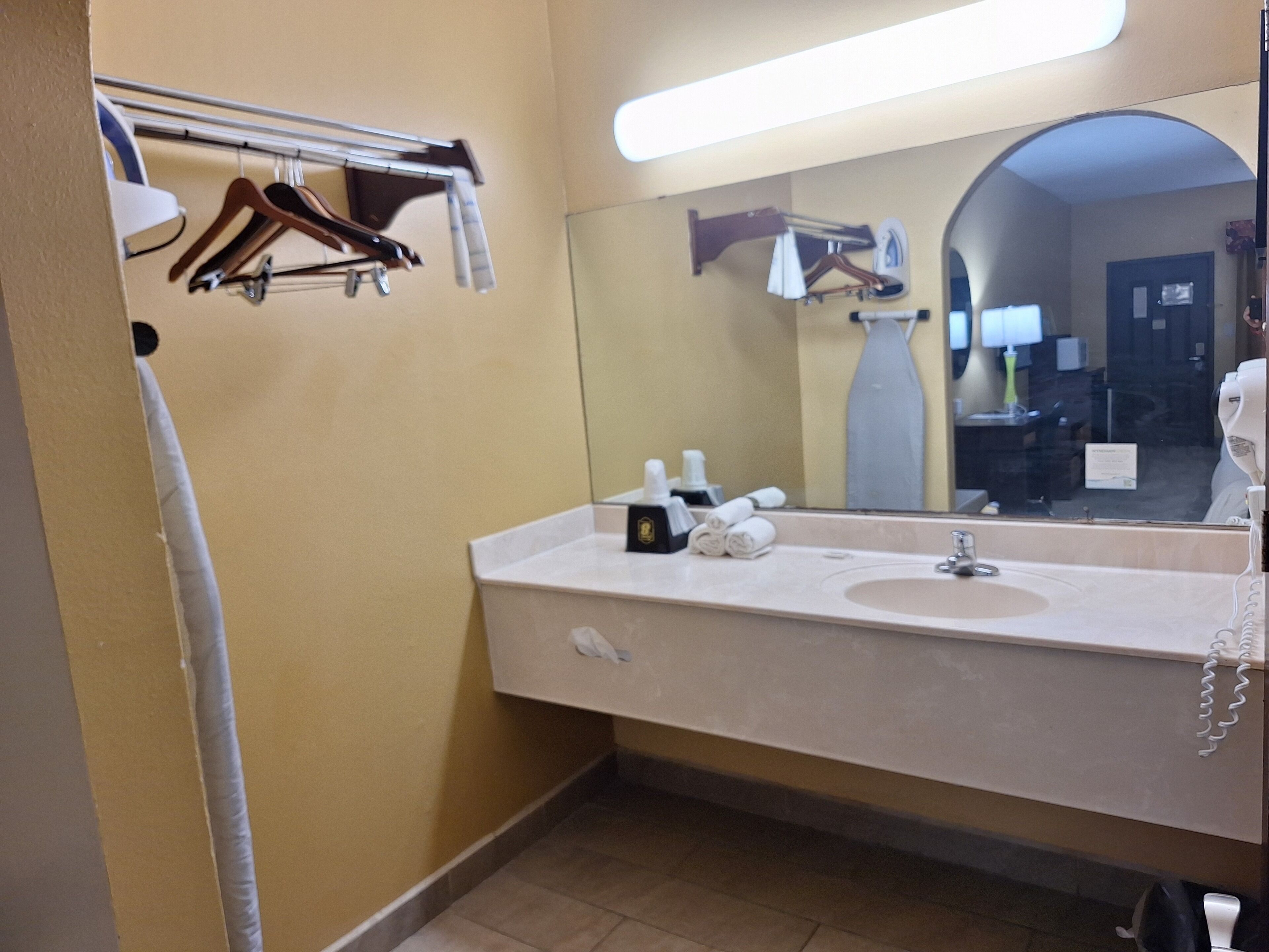 Ein Badezimmer mit Waschbecken, Spiegel, Handtuchhalter und Pflegeprodukten.