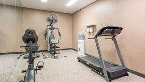 Un gimnasio con cinta de correr, bicicleta estática y ventilador.