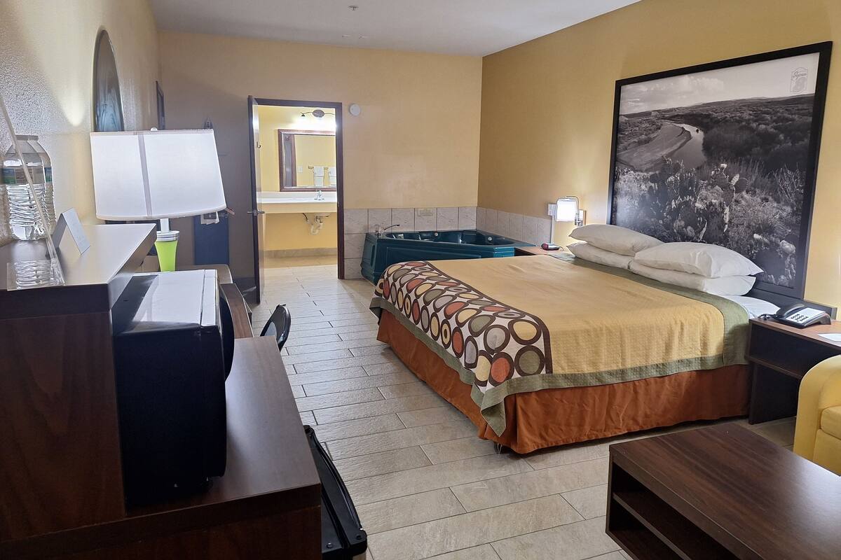 A hotel room with a bed, desk, chair, and a large window.