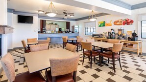 A dining area with tables and chairs, a kitchen counter, and a television mounted on the wall. - Quality Inn & Suites Gallup I-40 Exit 20 (Gallup)