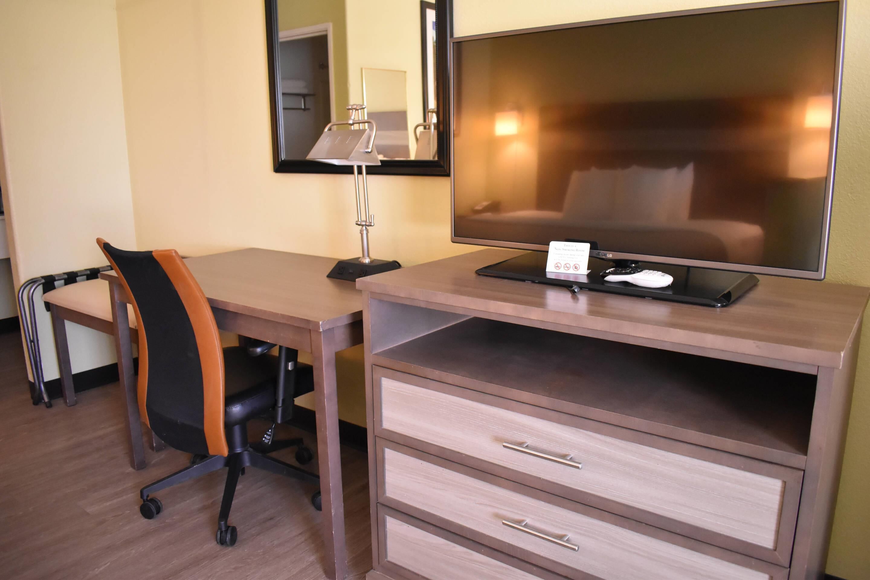 Una habitación de hotel con escritorio, silla, televisión y cama.