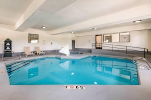 An indoor swimming pool with a 3 FT 9 IN depth marker, lounge chairs, and a small hot tub.
