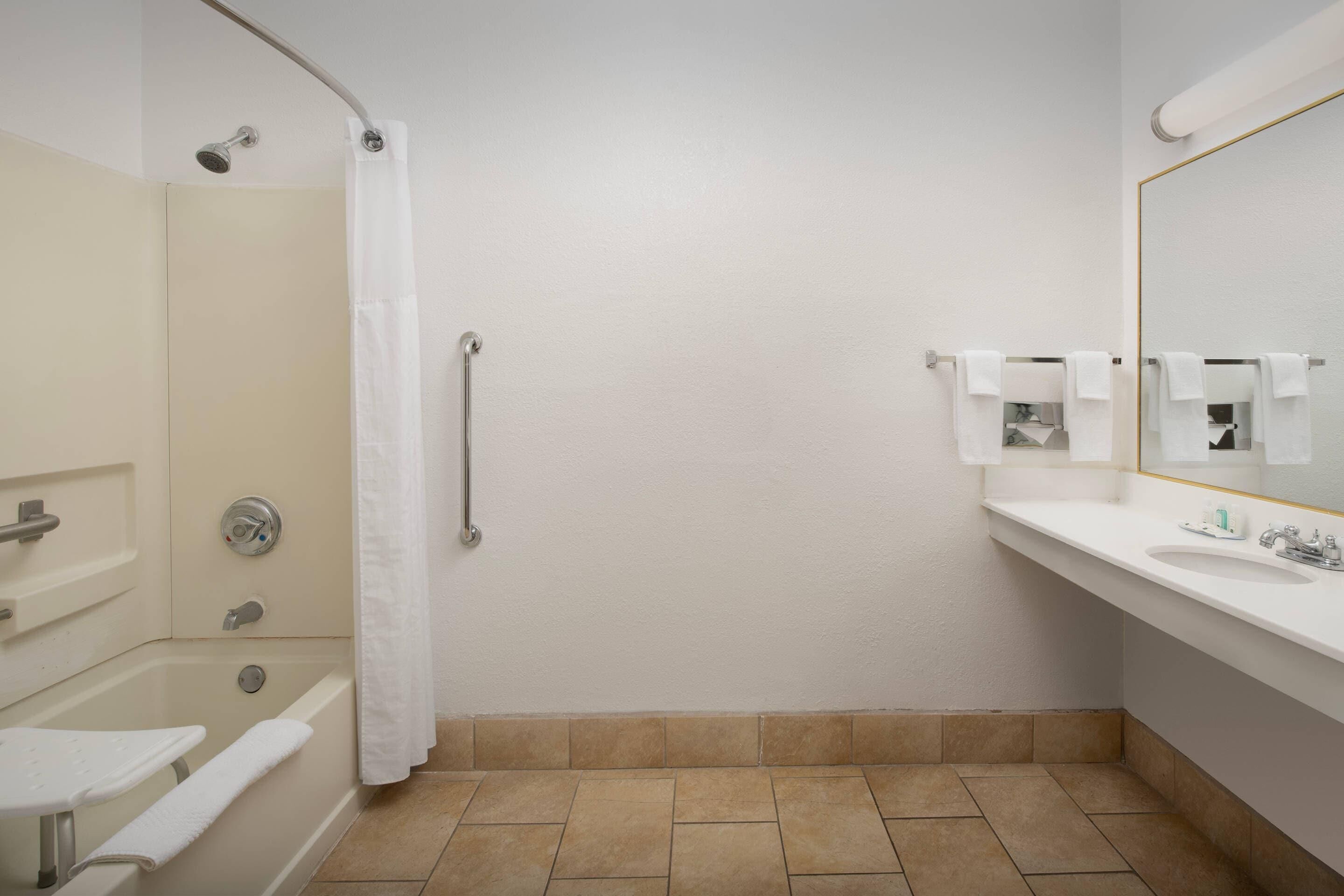 A bathroom with a bathtub, a shower, a sink, and a mirror.