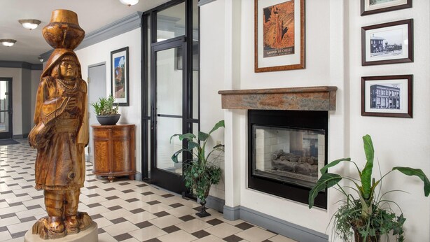 A lobby with a checkered floor, a wooden statue, a fireplace, framed pictures, and potted plants. - Quality Inn & Suites Gallup I-40 Exit 20 (Gallup)