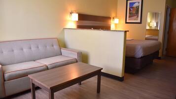 Habitación de hotel con sofá, una mesita, cama, mesita de noche y espejo.