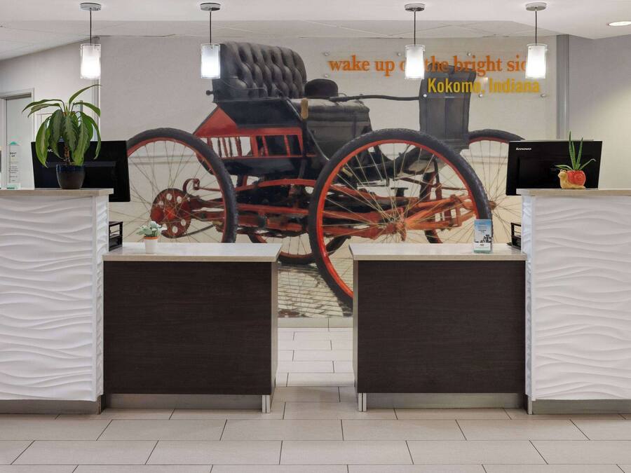 A reception desk with a large poster of a red carriage in the background.