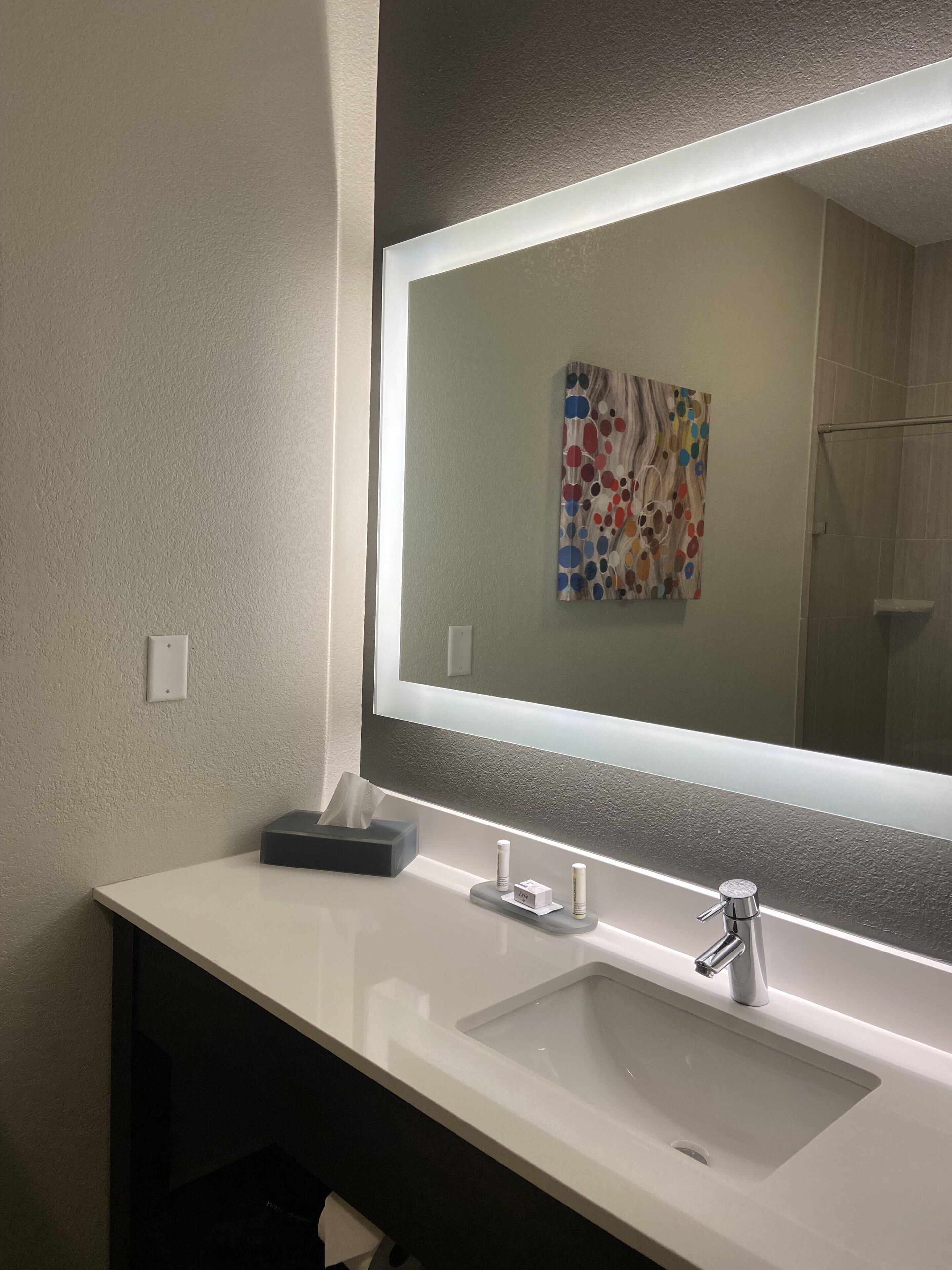 Une salle de bain avec un lavabo blanc, un miroir et un distributeur de serviettes.