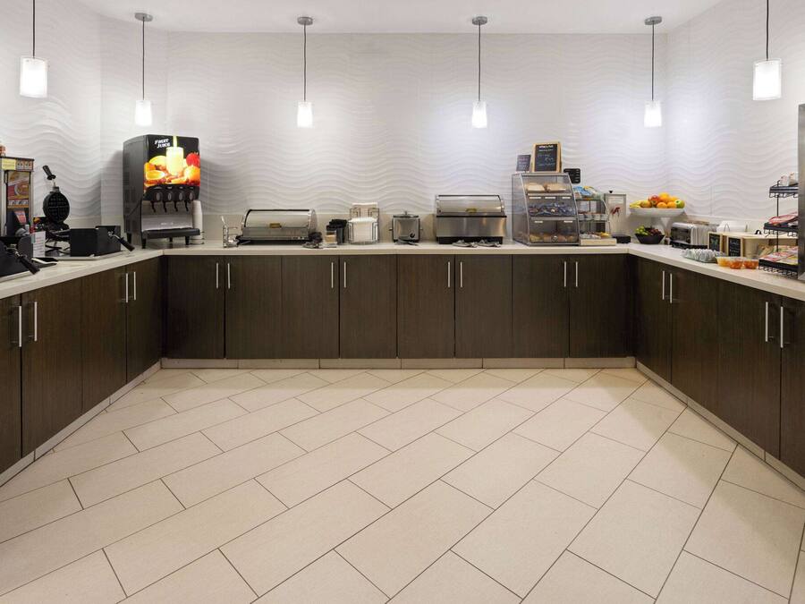 A modern kitchen with a central island, equipped with a coffee machine, toaster, and a fruit bowl.
