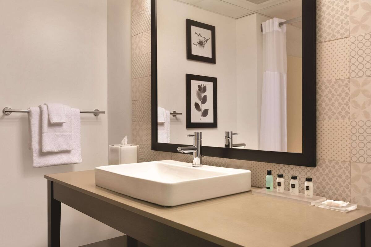A bathroom with a white sink, a large mirror, and a towel rack.