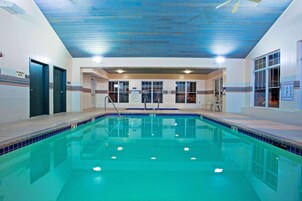 Una piscina interior con agua cristalina, cubierta de madera y paredes con azulejos.