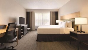 Une chambre d’hôtel comprenant un lit, un bureau avec une chaise, une télévision et une lampe.