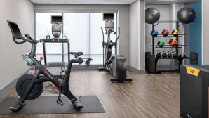 A gym with stationary bikes, a rowing machine, and a variety of exercise balls.