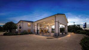 A modern hotel with a covered entrance, a satellite dish, and a sign indicating it is a Best Western hotel. - Best Western Inn (Clanton)