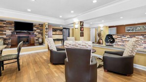 A modern living room with a fireplace, comfortable seating, and a flat-screen TV. - Best Western Inn (Clanton)