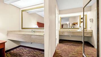Un baño de hotel con un espejo grande, un lavamanos y un suelo estampado.