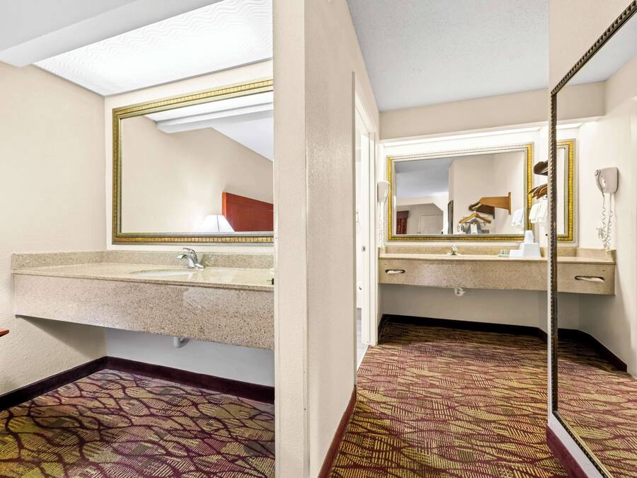 Un baño de hotel con un espejo grande, un lavamanos y un suelo estampado.