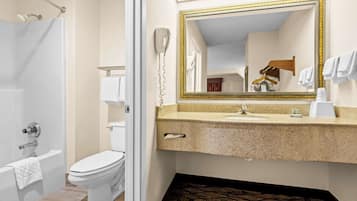 Une salle de bain avec des toilettes blanches, une baignoire, un lavabo avec un miroir et un porte-serviettes.
