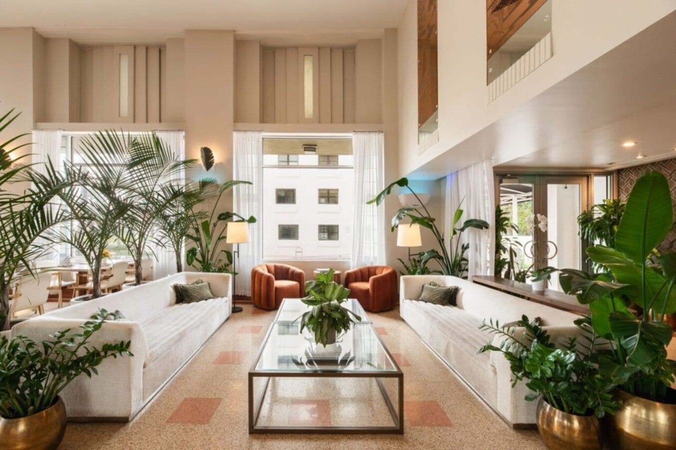 A spacious lobby with a central coffee table, seating area with sofas, and potted plants.