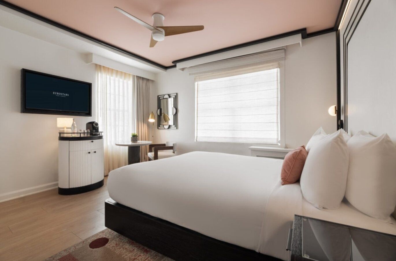 A hotel room with a bed, a desk, a television, and a window.