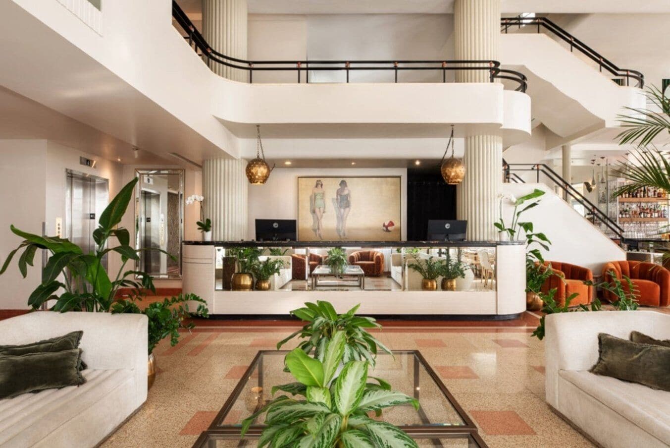 A spacious lobby with a central reception desk, seating areas, and a staircase.