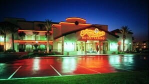 Ein Hotel mit einem Neonzeichen, auf dem 'Arizona Charlie's Hotel & Casino' steht, im Dämmerlicht.