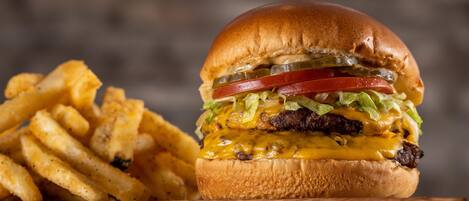 Un hamburger accompagné de frites, avec en arrière-plan une enseigne indiquant « PT'S EXPRESS ».