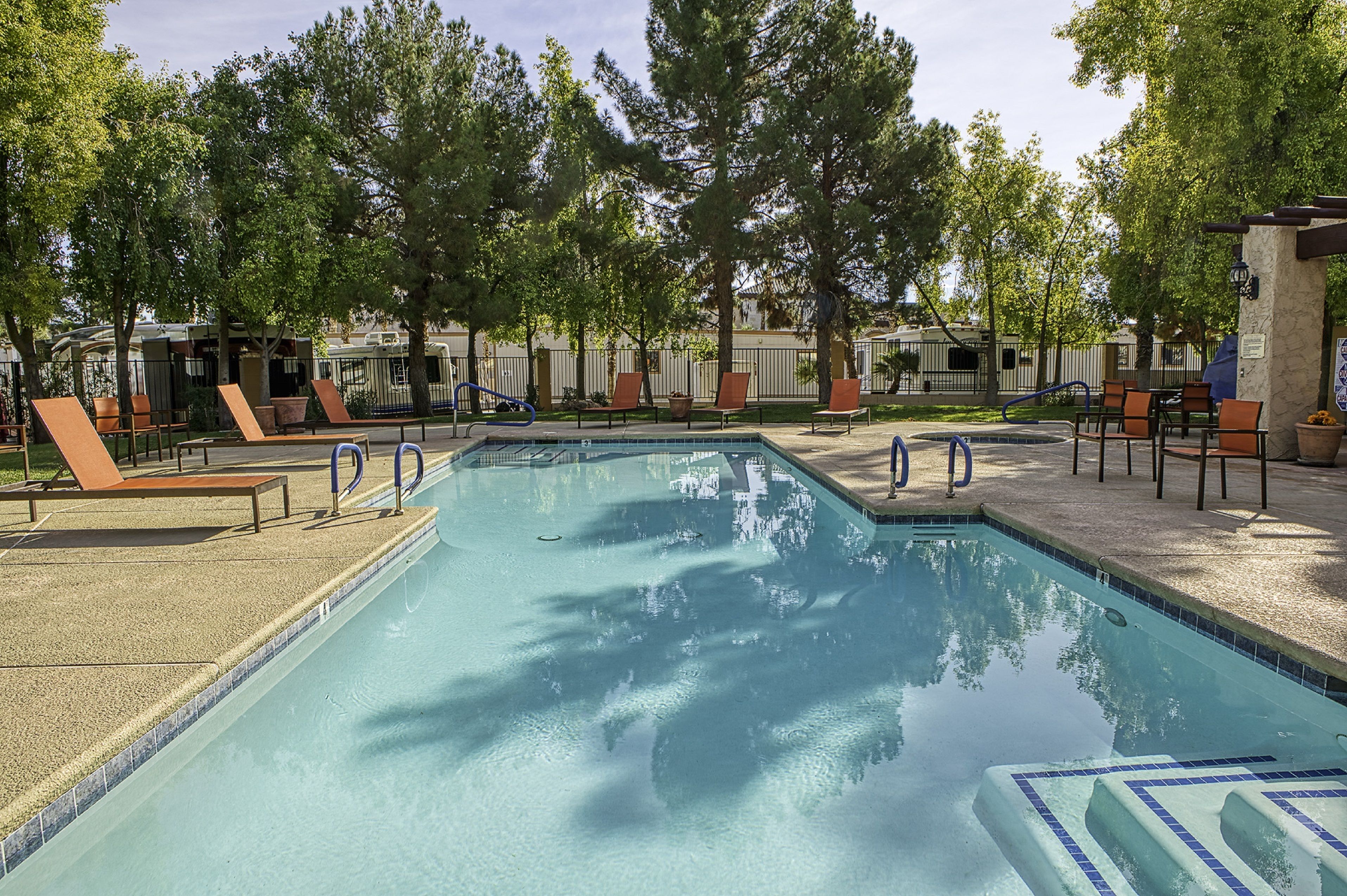 A rectangular swimming pool with a tiled edge, surrounded by lounge chairs and potted plants.
