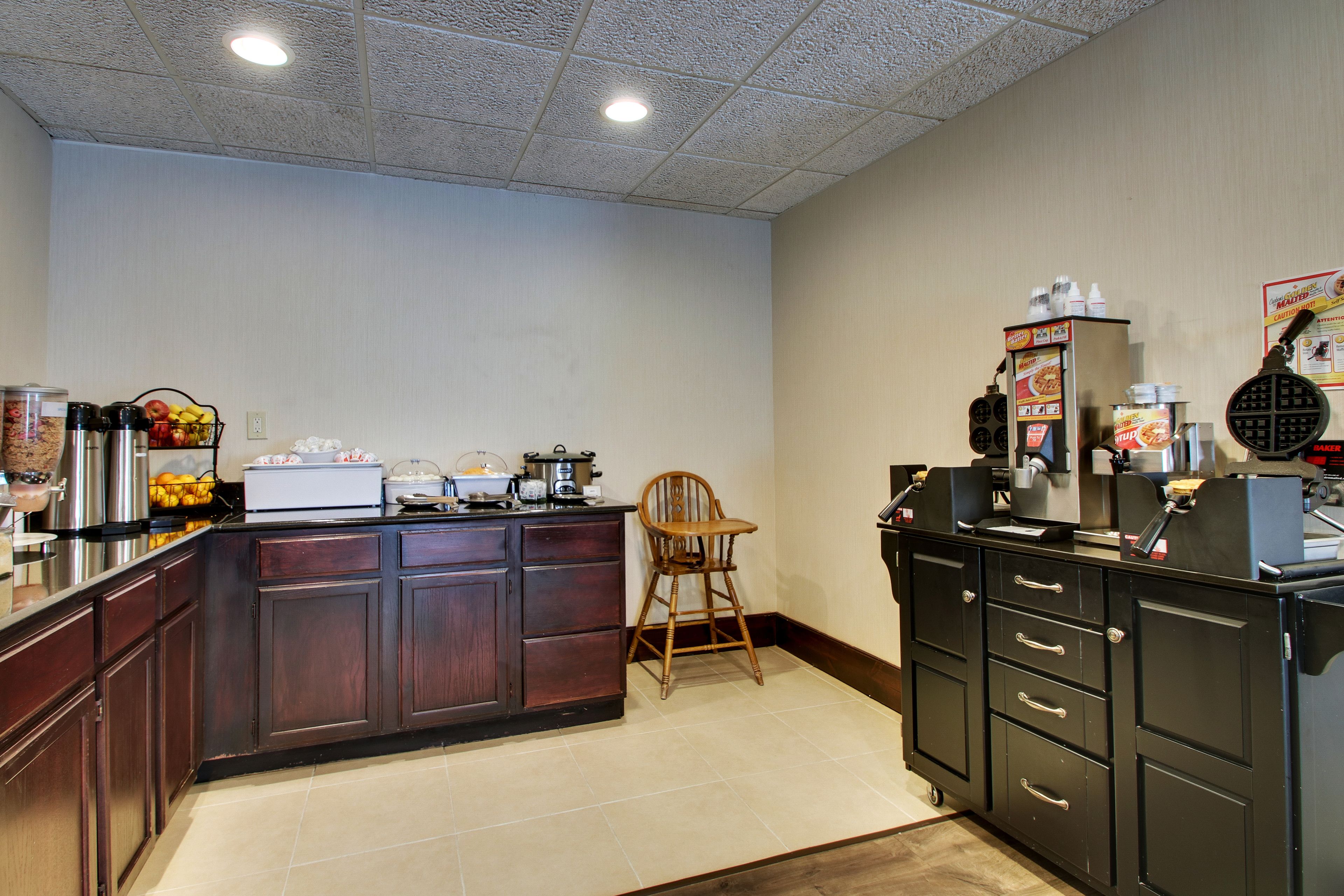 A kitchen with a wooden island, a chair, and various appliances.