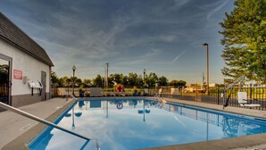 Una piscina con barandilla metálica, una silla de salvavidas y un cartel de prohibido bucear.