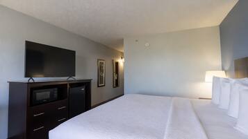 Una habitación de hotel con una cama, un televisor de pantalla plana, un microondas y un aparador.