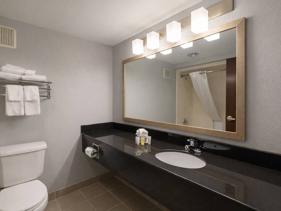 A bathroom with a toilet, sink, mirror, towel rack, and shower curtain.