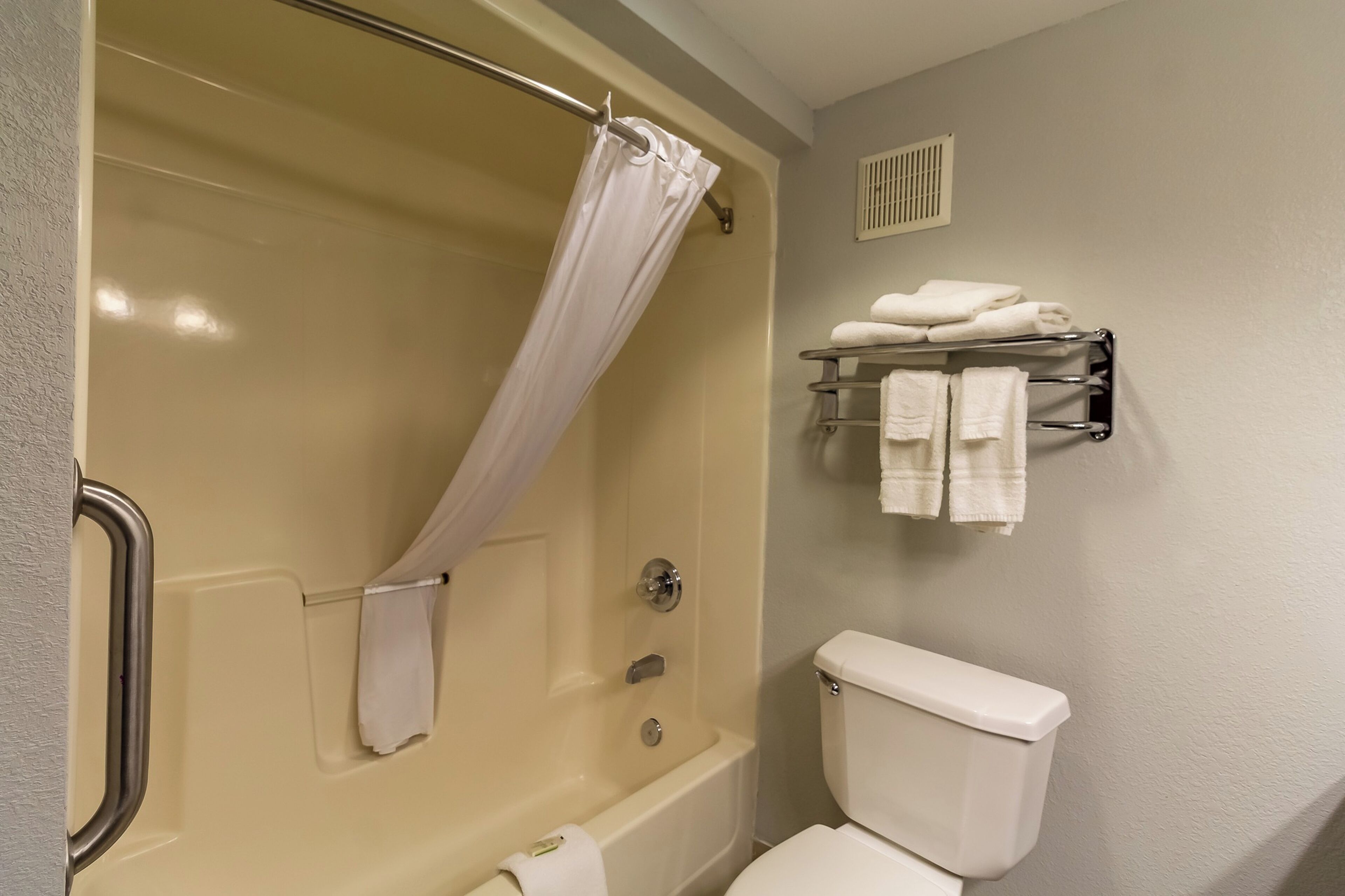 A bathroom with a bathtub, toilet, and a towel rack.
