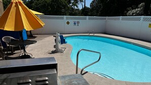 A swimming pool with a metal ladder, a white fence, and a yellow umbrella. - Super 8 by Wyndham Red Bluff (Red Bluff)