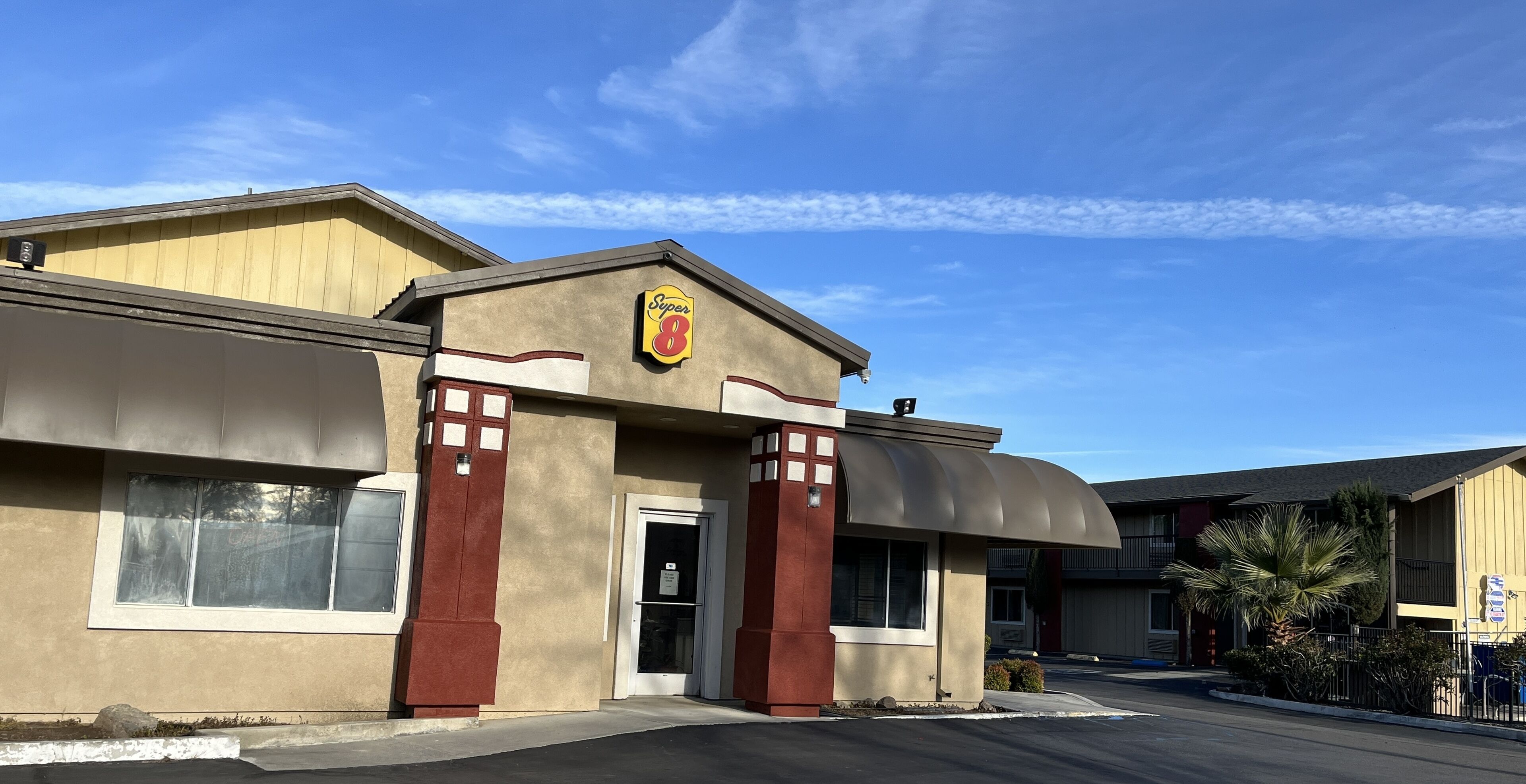 A Super 8 hotel with a beige facade, red accents, and a curved awning.