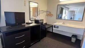 A hotel room with a flat-screen TV, a desk with a computer, a mirror, a sink, and a trash can. - Super 8 by Wyndham Red Bluff (Red Bluff)