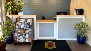 A reception area with a desk, a bulletin board with various items, and potted plants. - Super 8 by Wyndham Red Bluff (Red Bluff)