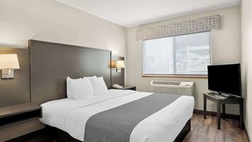 A hotel room with a large bed, bedside lamps, a flat-screen TV, and a window with blinds.