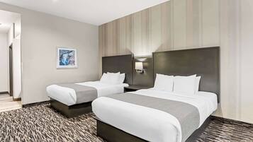 A hotel room with two beds, a large window, and a wall-mounted artwork.