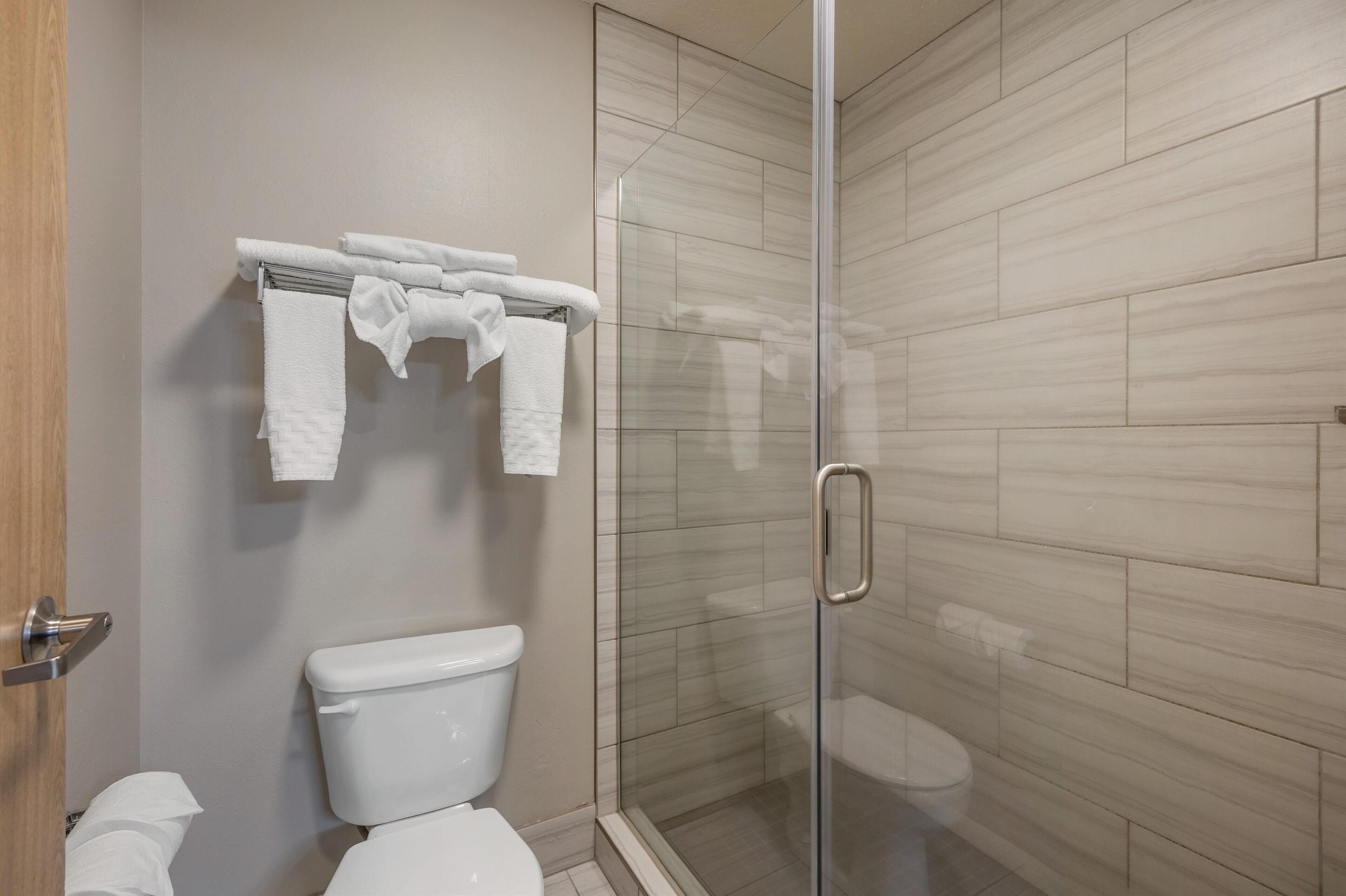 Un bagno moderno con box doccia in vetro, un water e un porta asciugamani con asciugamani piegati.