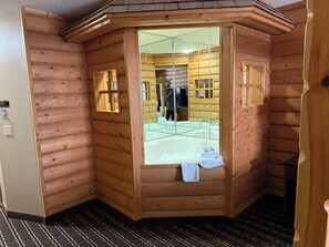 Eine Holzhütte mit einem gläsernen Duschbereich, einem Handtuch und einem Fliesenboden.